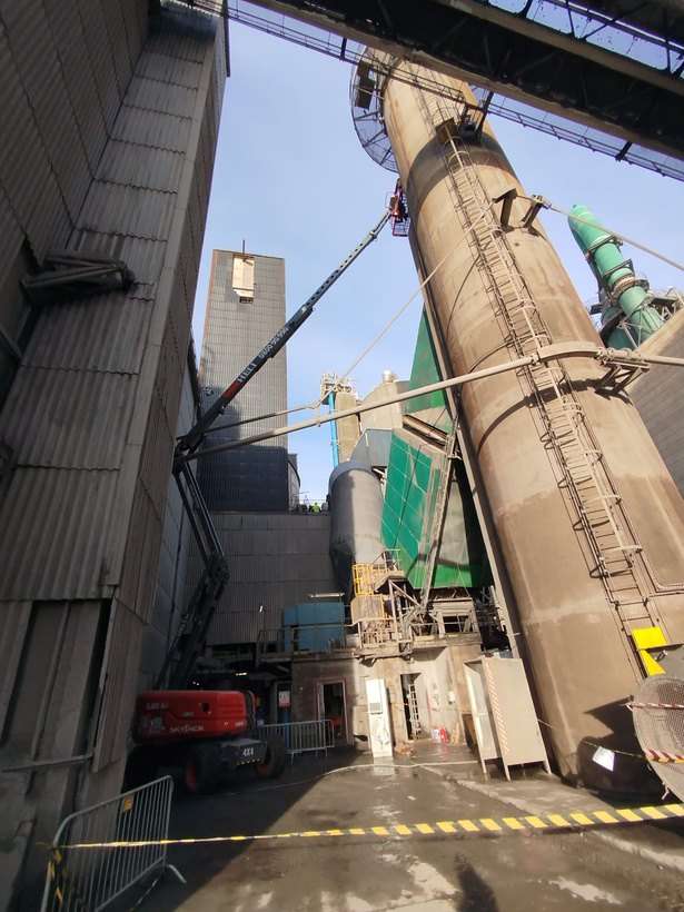 Tour et silo d'une cimenterie, nacelle élévatrice déployée vers une plateforme haute.